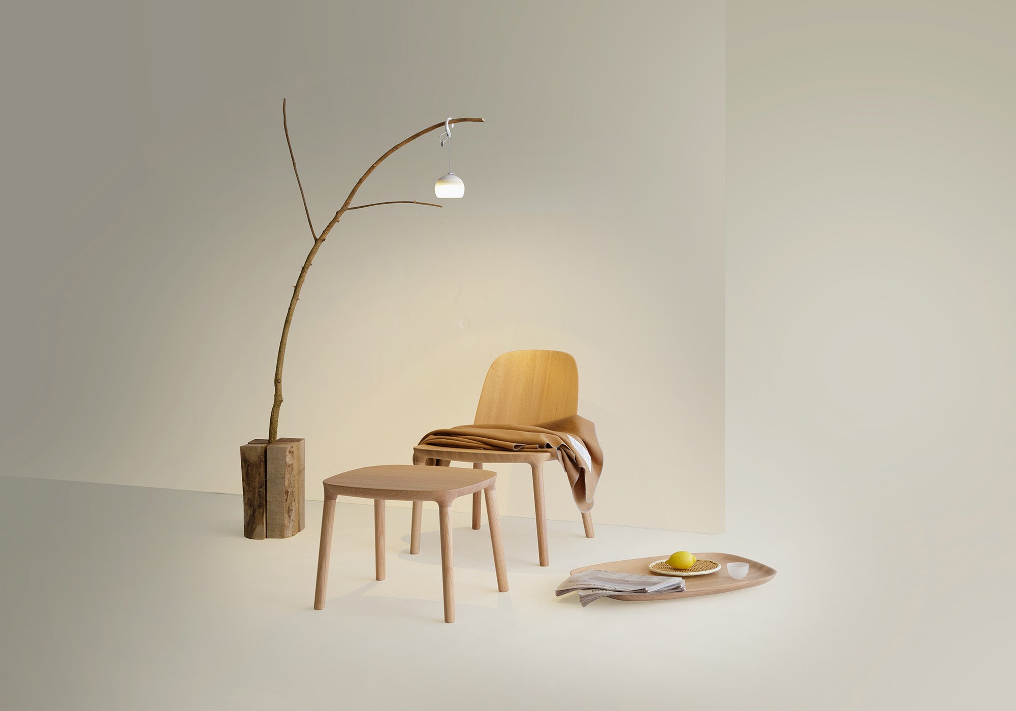 Kokoro Collection pieces, including a Lounge Chair in natural oak, Ottoman and tray used as side table arranged in a modern living space, demonstrating harmony with camping lamp.