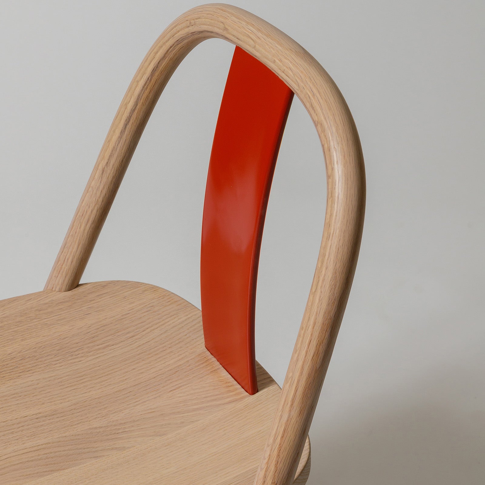 Close-up of the Chin-Chin chair’s red lacquered backrest, showing its smooth, glossy finish and precise craftsmanship.